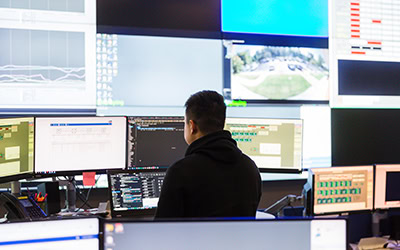 Employee looking at multiple monitors to asses the best course of action