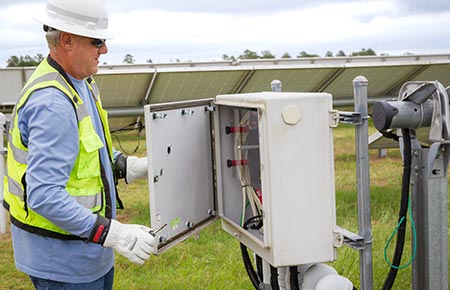 Engineer inspecting inverter on a solar farm.