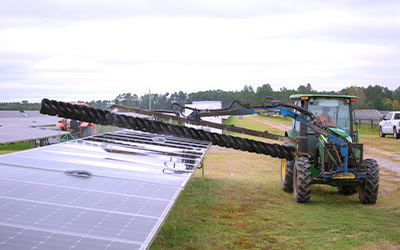 A tractor washing solar panels with a very long brush to grant the most coverage and efficiency