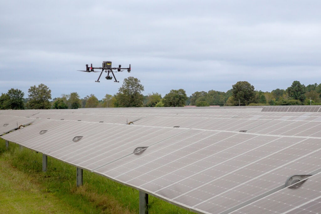 A drone flies over a row of solar panels