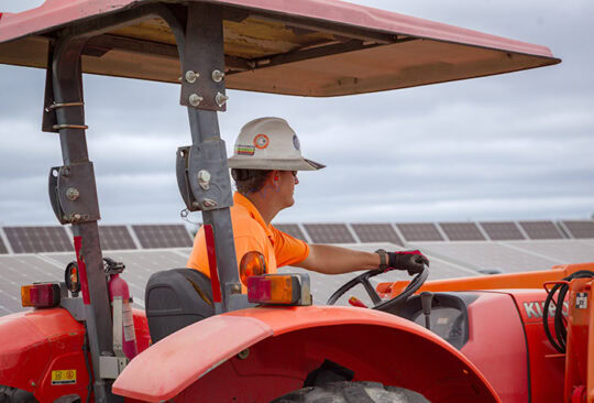 A man drives a tractor on a solar farm