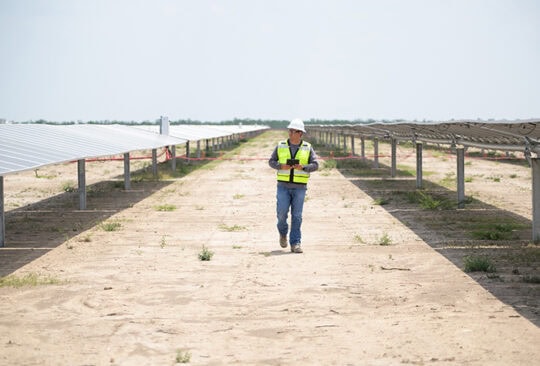 A man walks down a row of solar panels